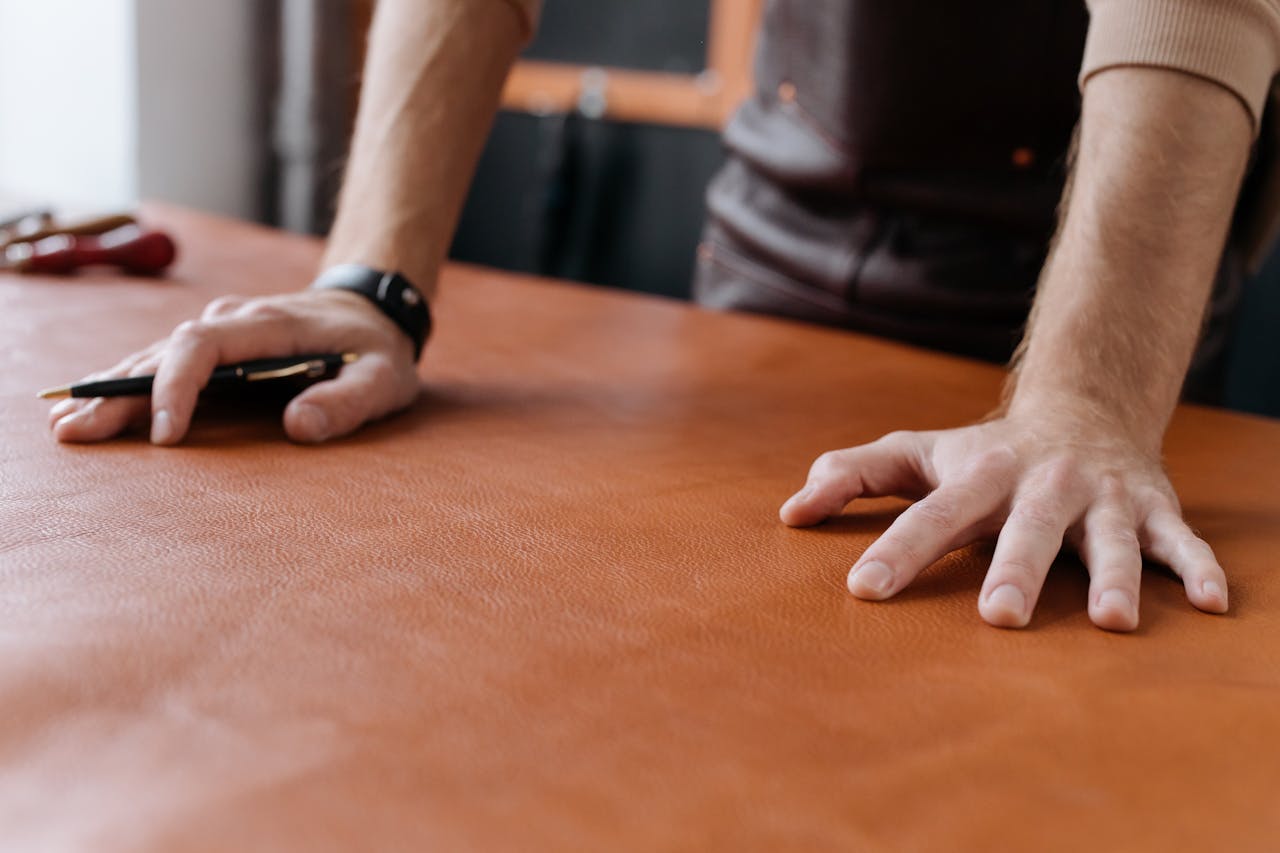 The Art of Drawing Readers In: Your attractive post title goes here Detailed shot of a leatherworker’s hands working with brown leather, highlighting craftsmanship and precision.